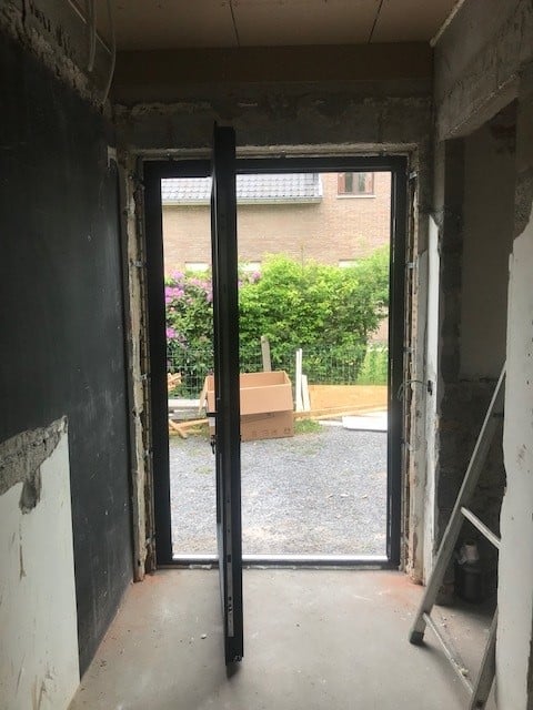 zwarte aluminium buitendeur met draaisysteem geïnstalleerd door DRJ RAMEN & DEUREN in moderne woning