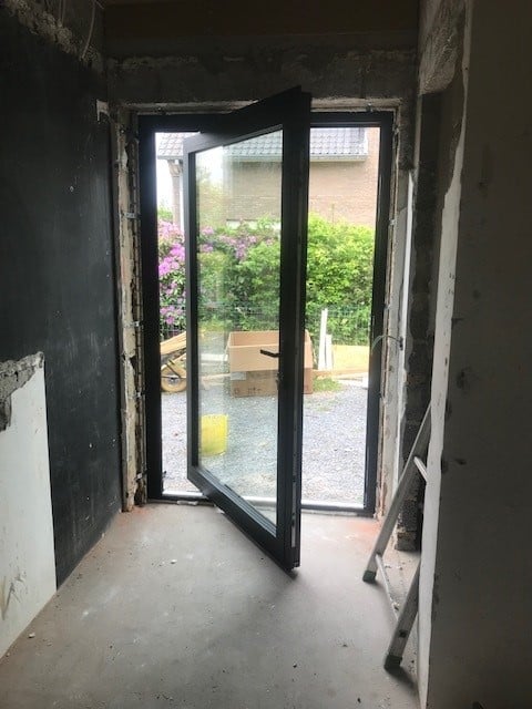 zwarte aluminium buitendeur met draaisysteem geïnstalleerd door DRJ RAMEN & DEUREN in moderne woning