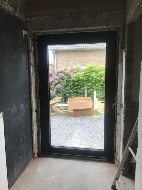 zwarte aluminium buitendeur met draaisysteem geïnstalleerd door DRJ RAMEN & DEUREN in moderne woning