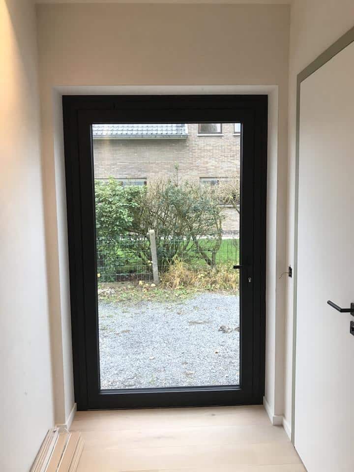 zwarte aluminium buitendeur met draaisysteem geïnstalleerd door DRJ RAMEN & DEUREN in moderne woning