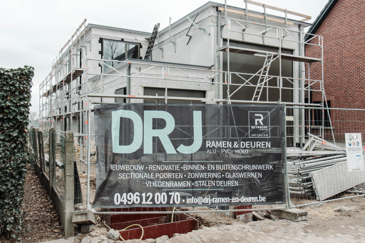 Wervenbord met logo en diensten van DRJ Ramen & Deuren op bouwwerf – over DRJ