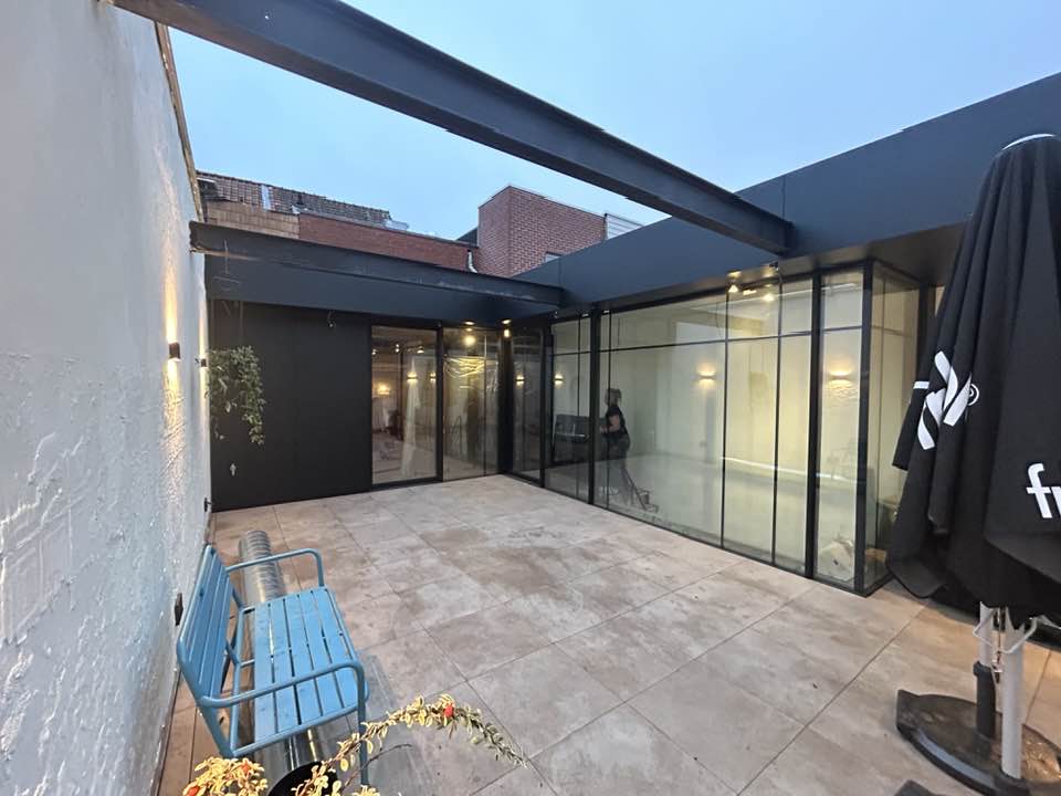 avondzicht op patio met volglazen gevel en verlichting